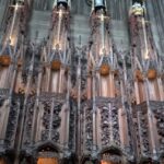 Intrincados paneles de madera tallada gótica en un coro eclesiástico, con pináculos y motivos vegetales; ¡Descubre cómo plantar cardos de Escocia y embellece tu jardín!