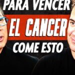 Dos hombres conversando frente a un cartel grande con el texto EL CANCER en rojo y negro, expresiones serias y sonrientes, Descubre el Secreto para Cultivar Calabazas Espaguetis ¡Sorprendente!