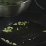 Secreto para plantar endibias rizadas: sartén con ajo en aceite sobre placa vitrocerámica.